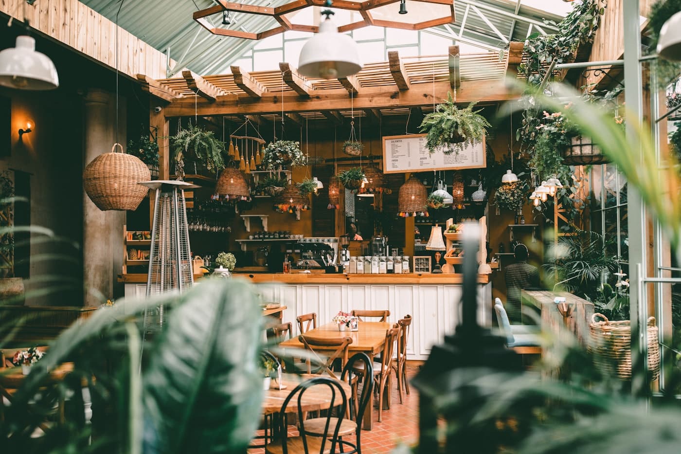 Warm, plant-filled café interior with a wooden bar